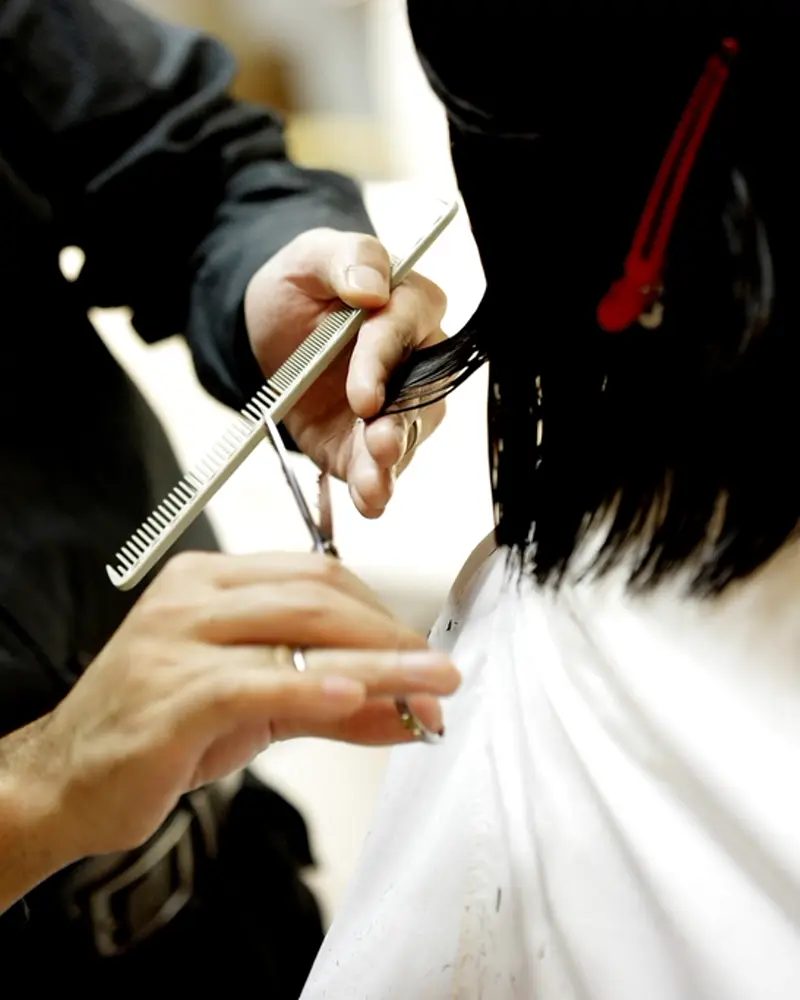Estilista cortando cabello con tijera y peine