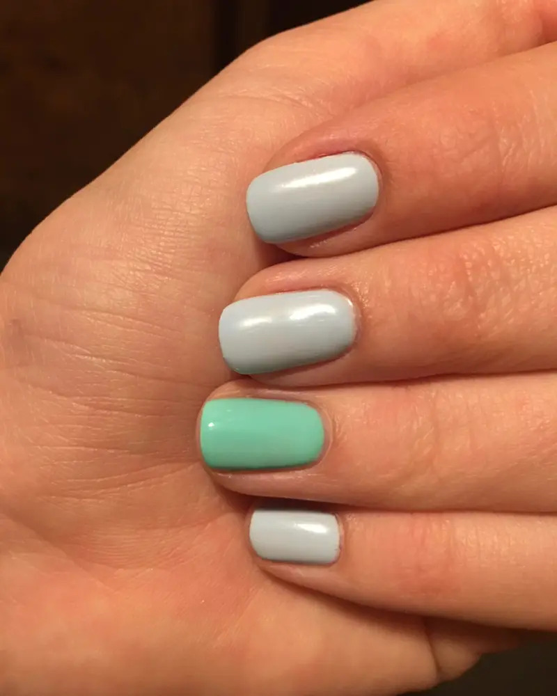Uñas cortas en gris perla con una en verde agua