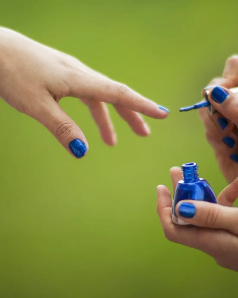 Manicura aplicando esmalte azul